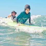 Surfinstruktören väljer rätt våg och ger surfbrädan en liten knuff