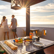 Gäster njuter av frukost på den soliga terrassen på vårt surfcamp på Fuerteventura.